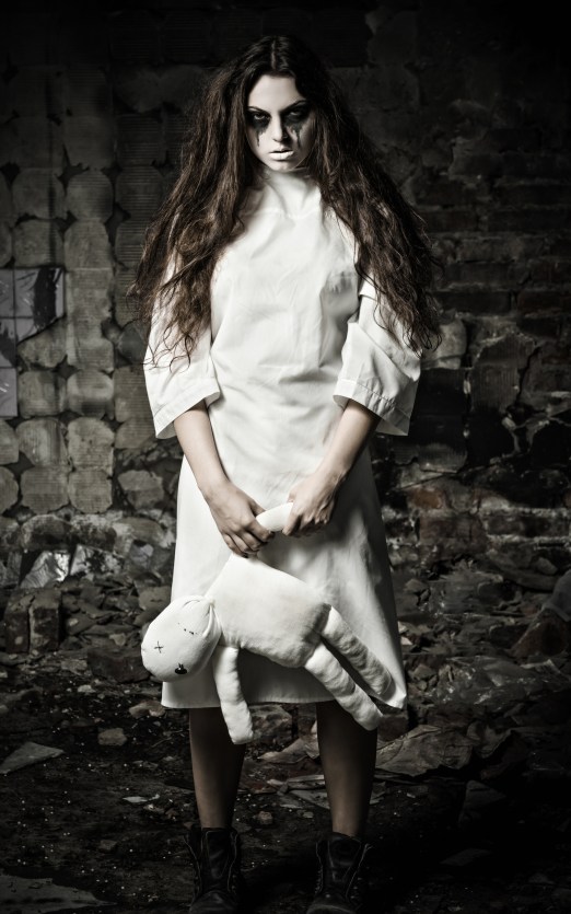 Horror style shot: scary monster girl with moppet doll in hands